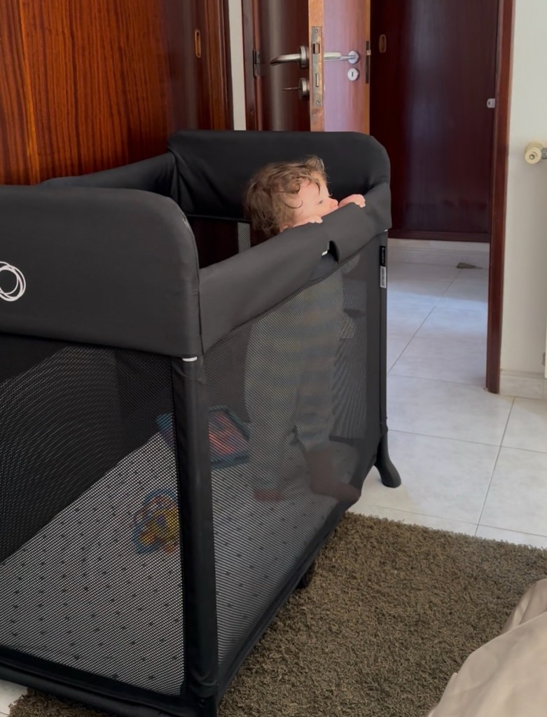 Toddler sleeping in portable travel cot in hotel